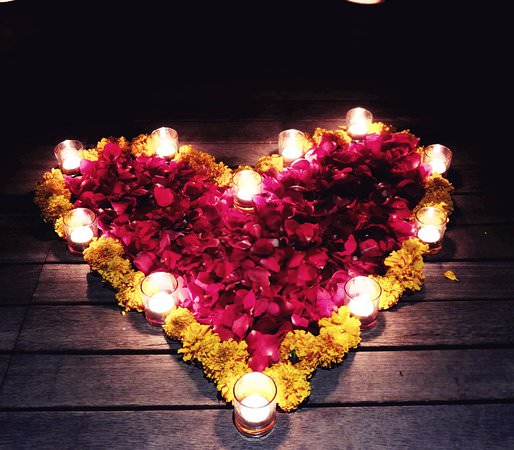 کفپوش چوبی که روی آن به وسیله گل های زرد و قرمز و چندین شمع به شکل قلب تزیین شده است